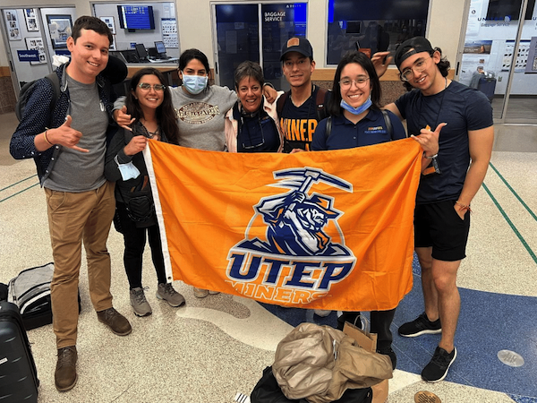 Dr Santiago and a group of students holding an orange UTEP flag